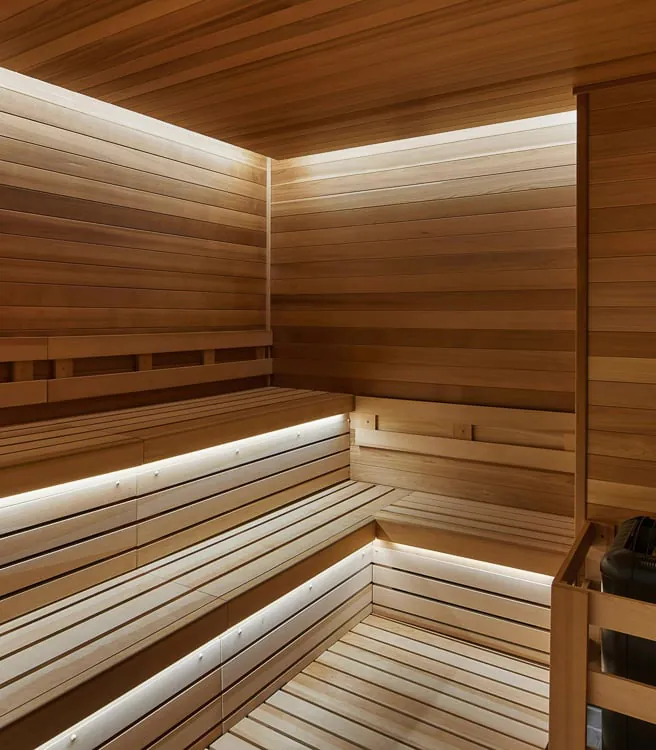 Sauna obložena drvetom sa stepenastim sedištima i mekim LED osvetljenjem duž klupa.