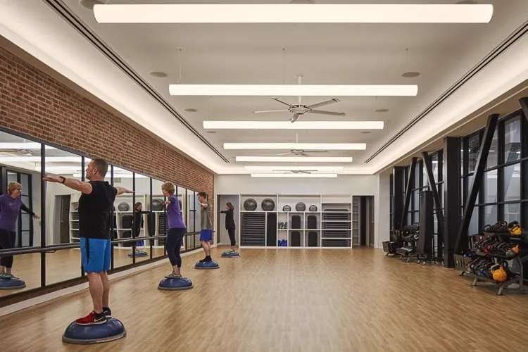 Grupni fitnes čas sa balans trenažerima u studiju sa ogledalima, drvenim podom i prirodnim svetlom.